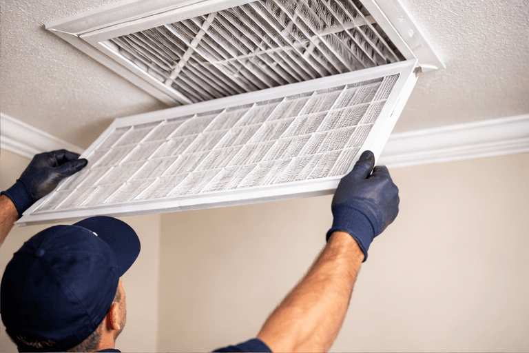 Technician replacing a residential HVAC air filter during maintenance service